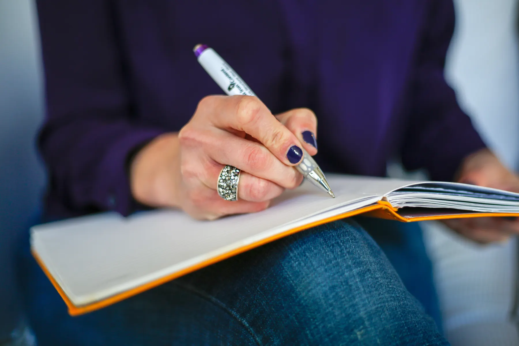 A hand writing in a lined notebook with a fountain pen